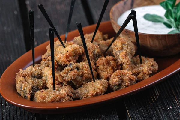 Snacks for beer on dark wood background. Fried chicken hearts with sauce