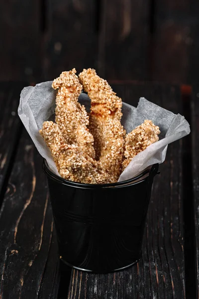 Snacks for beer on dark wood background. Chicken fried breast in a black small bucket