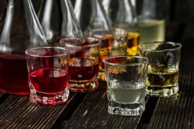 Gözlük ve koyu ahşap arka plan üzerinde sürahilere çeşitli alkollü yabanî