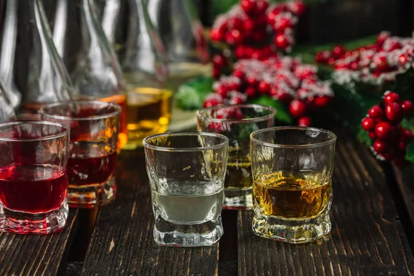 Gözlük ve koyu ahşap arka plan üzerinde Noel süslemeleri ile sürahilere çeşitli alkollü yabanî