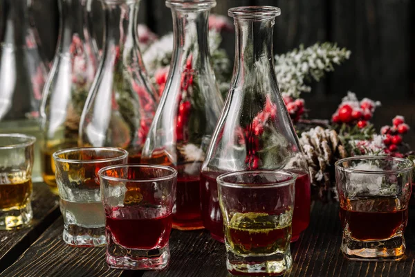 Gözlük ve koyu ahşap arka plan üzerinde Noel süslemeleri ile sürahilere çeşitli alkollü yabanî