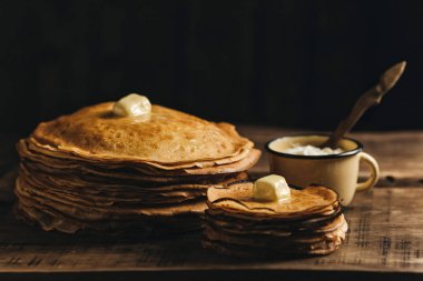 Tereyağı ve ahşap arka plan üzerinde meyveleri ile krep yığını.  