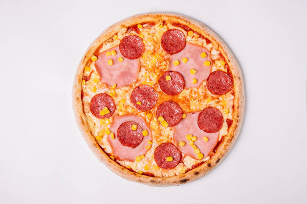 Пицца с салями, ветчиной и кукурузой изолированы на белом. Вид сверху
