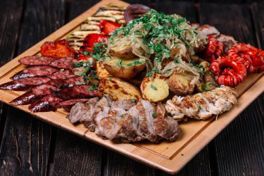 Çeşitli lezzetli ızgara et, sosis ve sebze köklerine üzerinde