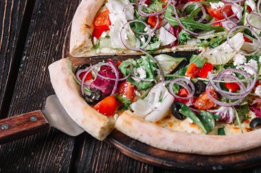 Vejeteryan pizza ve spatula ahşap arka plan üzerine dilimlenmiş  