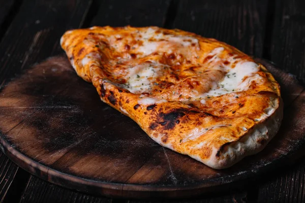 Calzone - nadziewane Pizza z pomidorów, mozzarelli i szynki na drewno — Zdjęcie stockowe