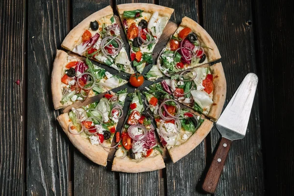 Sliced vegeterian pizza and spatula on wood background — Stock Photo, Image