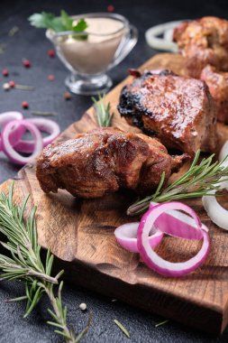 Biberiyeli şiş kebap, soğan ve tahta kesme tahtasında beyaz sos. Siyah arkaplanda 