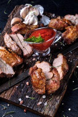 Biberiyeli taze şiş kebap ve tahta kesme tahtasında iki çeşit sos. Siyah arkaplanda 