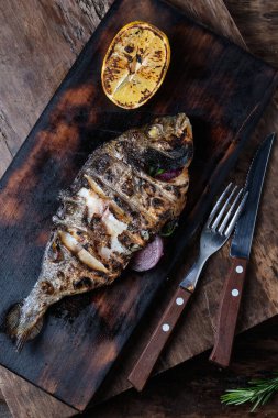 Izgara Dorado ahşap arka planda kesim tahtasında servis edilir.