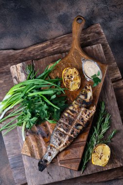 Izgara alabalık kesim tahtasında servis edilir. Ahşap arka planda. Üst görünüm