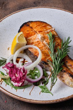 Siyah arka planda beyaz tabakta ızgara somon.