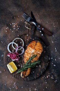 Kesme tahtasında ızgara somon ve arka planda çatal bıçak.