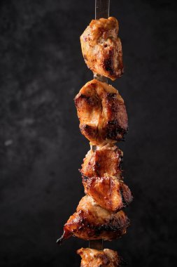 Izgara tavuk eti şişi, siyah arka planda şiş kebap