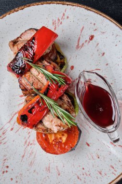 Beyaz tabakta ızgara dana eti ve ızgara sebze ve koyu beton arka planda kiraz sosu. Üst görünüm