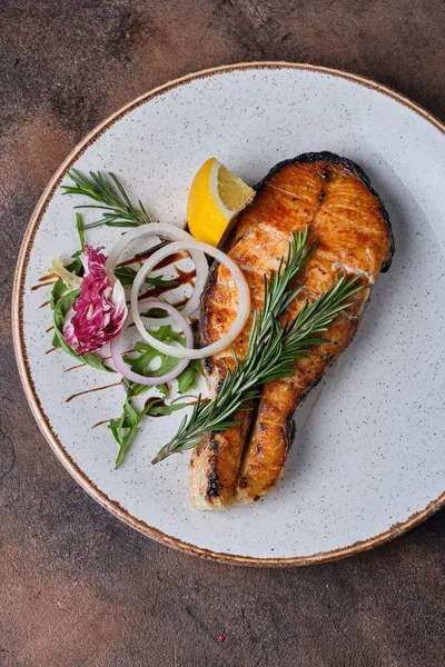 Siyah arka planda beyaz tabakta ızgara somon.