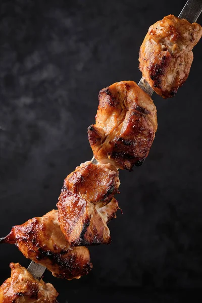 Izgara tavuk eti şişi, siyah arka planda şiş kebap