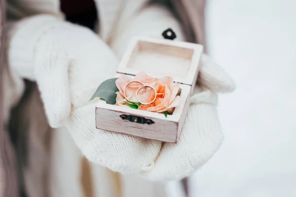 gloved hands holding wedding rings