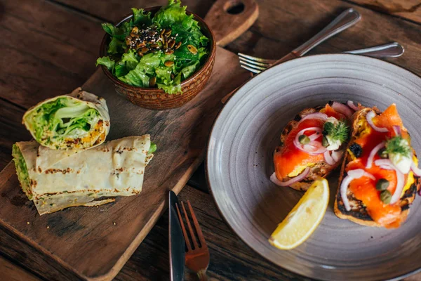 Rotoli con erbe aromatiche e insalata, pane tostato con salmone — Foto Stock