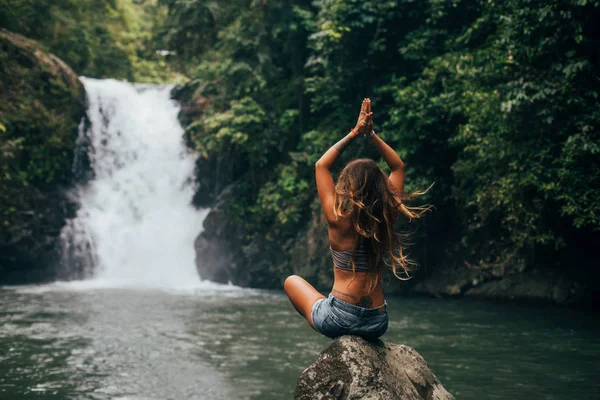 Girl meditates near waterfall — Stock Photo, Image