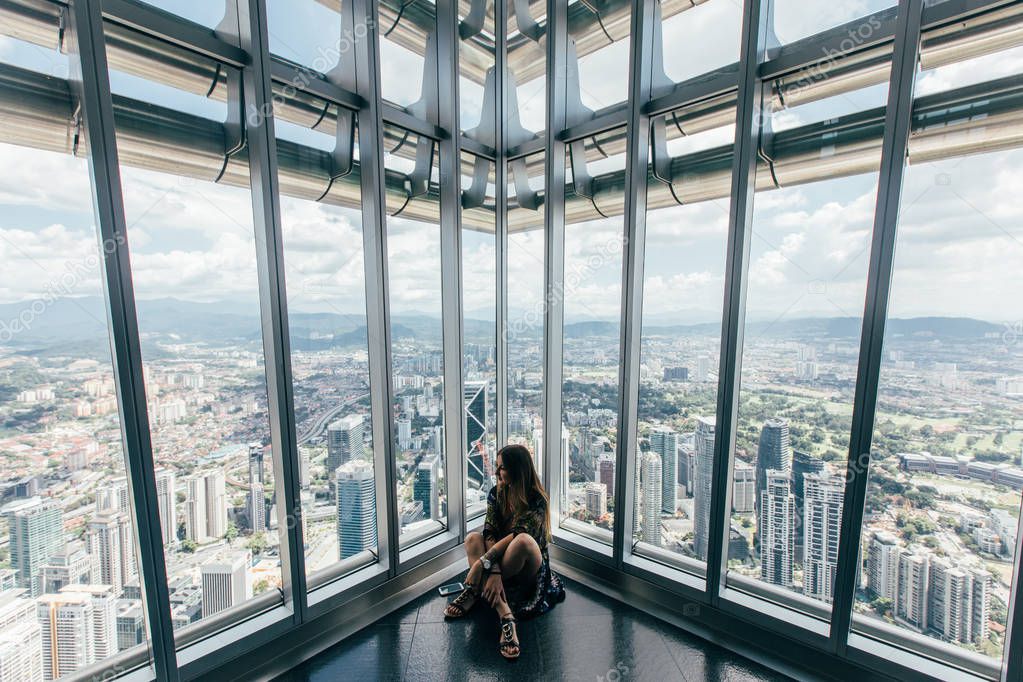 woman sitting on floor and looking at cityscape