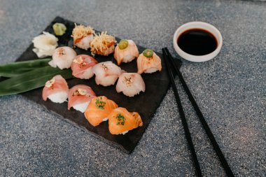 Siyah taş tabakta suşi ve soya sosu kasede ve çubuklarda, yakın görüş.
