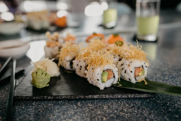 sushi on black stone plate and chopsticks, close view