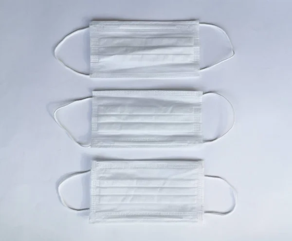 Three white medical masks on a white background, top view. Medical mask for protection against influenza virus and crown on a white background. Space for text. Symbol of medical expenses.