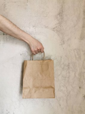 Bej arka planda eko paket. Bir adam el çantası tutuyor. Teslimat hizmeti konsepti. Paketleme şablonu modeli. Mesaj için yer var. Reklamcılık.