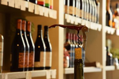 Şarap dükkanındaki ahşap rafta şarap şişeleri ve tirbuşonlu mantarlar