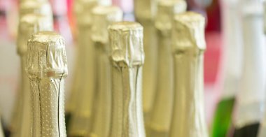 Şampanya altın şişe boyunlu ve hisse senedi ışık arka plan ayakta, üst kapaklar.