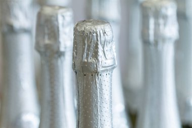 Gümüş şampanya şişe boyunlu ve tekel ışık arka planda duran, üst kapaklar.