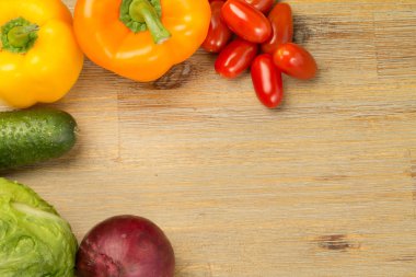 Sebze etrafındaki ahşap masa arka plan üzerinde. Cherry Domates, salatalık, yeşillik, kesme tahtası, biber portakal ve sarı, kırmızı soğan. Vegan veya vejetaryen. Sağlıklı beslenme. Salata.