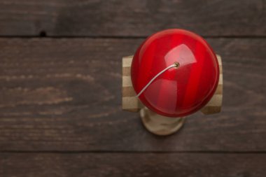 Koyu ahşap rustik arka plan üzerinde kırmızı kendama duran. Geleneksel Japon oyuncak. Doğruluk ve çeviklik geliştirme. Çocuklar, çocuklar, top oyunu.