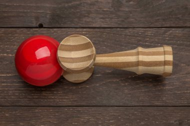 Kırmızı kendama koyu ahşap rustik arka tarafta döşeme. Geleneksel Japon oyuncak. Doğruluk ve çeviklik geliştirme. Çocuklar, çocuklar, top oyunu