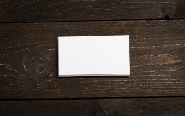 Koyu çikolata ahşap arka plan beyaz boş iş kartları yığını. Boş boş yatay kimlik belgelerini şablonu veya mockup yığını.