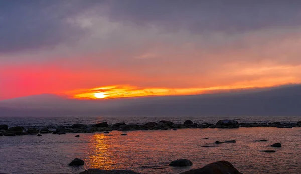 Hermosa puesta de sol dorada en el mar con cielo saturado, montañas y nubes. Reflejo en el agua. Línea costera rocosa. Paisaje tranquilo y sereno. Fondo de naturaleza . — Foto de Stock