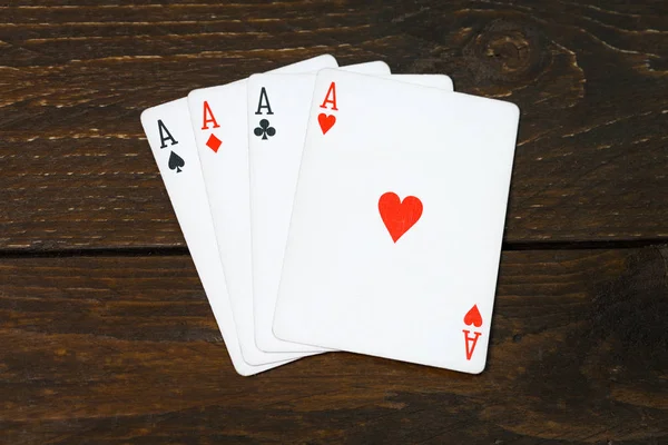 İskambil poker oyunu texas eski ahşap masa kavramı üzerinde üç as. Dört tür bir as. Ahşap arka plan casino şans. Risk başarı servet fikir vintage mobilya.