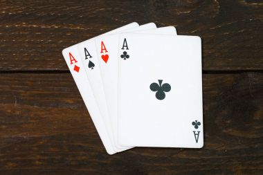 kart üzerinde Brown oyunları Casino ahşap masa veya Resepsiyon vintage renk koyu tonu tarzı görünüm üst kaba doku, dört as, yukarıda kulüpleri bir çete. Kare as Poker.