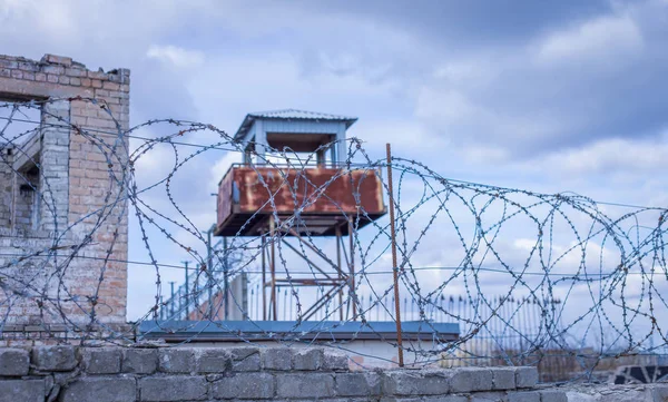 Historic brick prison wall showing guard tower and coiled barbed wire — Stock Photo, Image