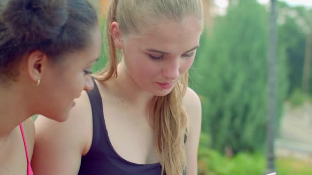 Blond dziewczyna rozmawia z afro dziewczyna w parku — Wideo stockowe