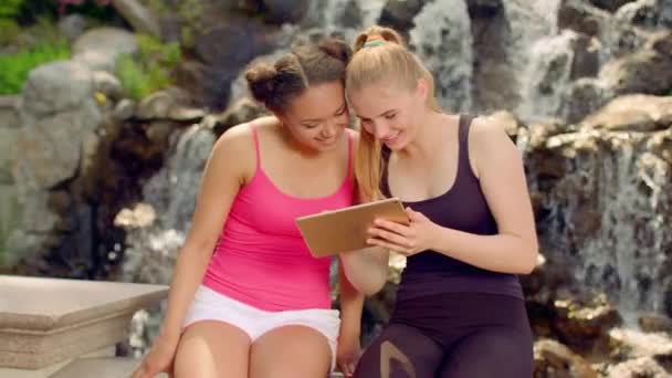 Chicas divirtiéndose con la tableta al aire libre. Gilfriends descansando en la naturaleza — Vídeos de Stock