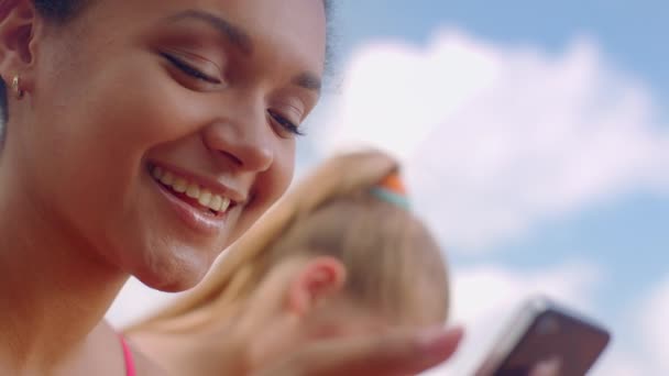 Flickan ler när läsa bra nyheter på telefon. Närbild av afrikansk flicka ansikte — Stockvideo