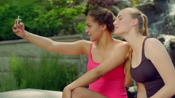 Two girlfriends taking photos in park. Girls selfie outdoor. Happy girlfriends — Stockvideo
