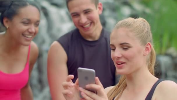 Amigos alegres viendo fotos en el teléfono inteligente — Vídeos de Stock