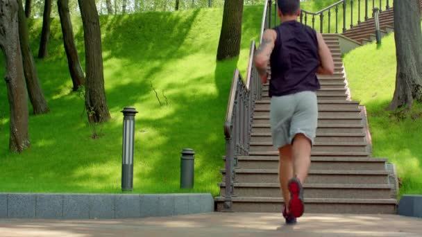 Joven corriendo escaleras arriba en el parque — Vídeo de stock