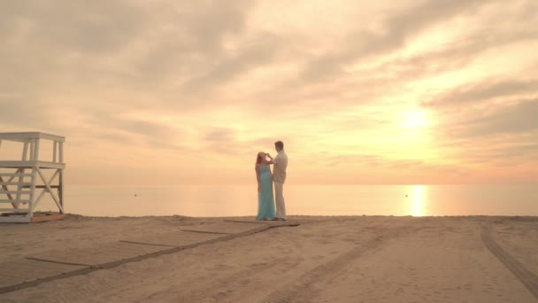 Coppia incinta sulla spiaggia di mare. L'uomo raddrizza i capelli della sua donna incinta — Video Stock