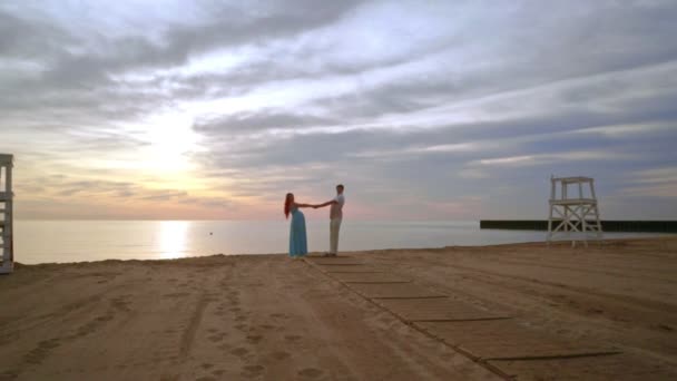 Terhes pár tánc tengerre tengerparton naplementekor. Boldog pár. Várandós szülők — Stock videók