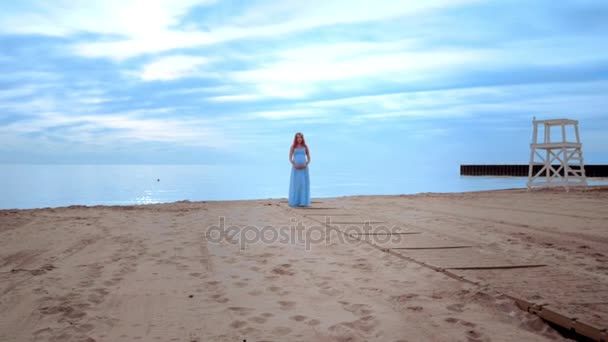 Gravid kvinna i lång klänning på stranden. Graviditet-konceptet — Stockvideo