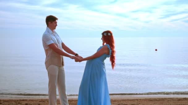 젊은 사람들이 바다 해변에 들고 손에. 임신 커플 비치 — 비디오